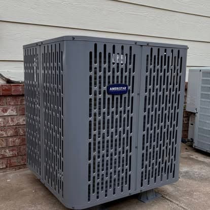 Ameristar outdoor air conditioning unit on a patio next to a brick wall.